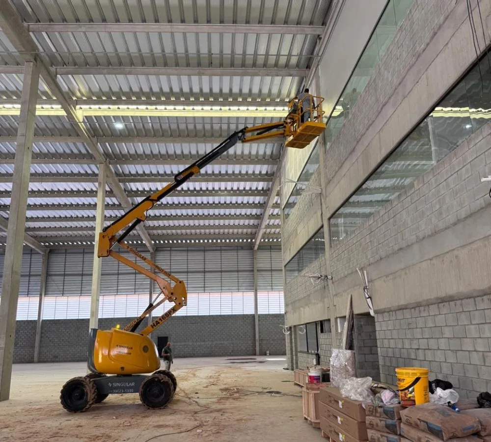 Plataforma articulada posicionada para inspeção de fachada interna em galpão